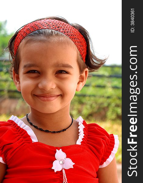 A small girl dressed in red frock smiling pleasantly. A small girl dressed in red frock smiling pleasantly.
