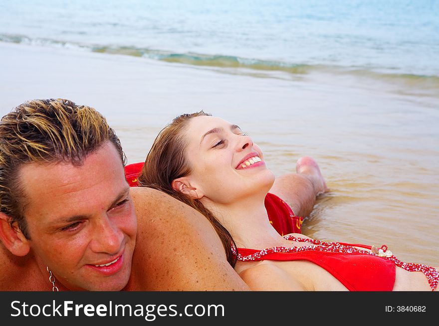 A portrait of attractive couple having fun on the beach. Focused on girlâ€™s face. A portrait of attractive couple having fun on the beach. Focused on girlâ€™s face.