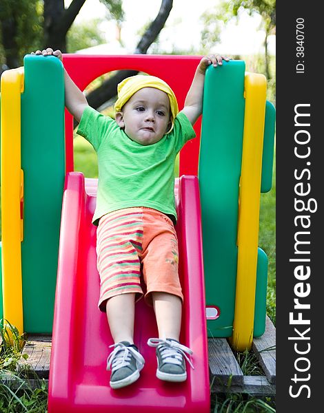 A cute caucasian boy playing on a colorful slide outdoors. A cute caucasian boy playing on a colorful slide outdoors.