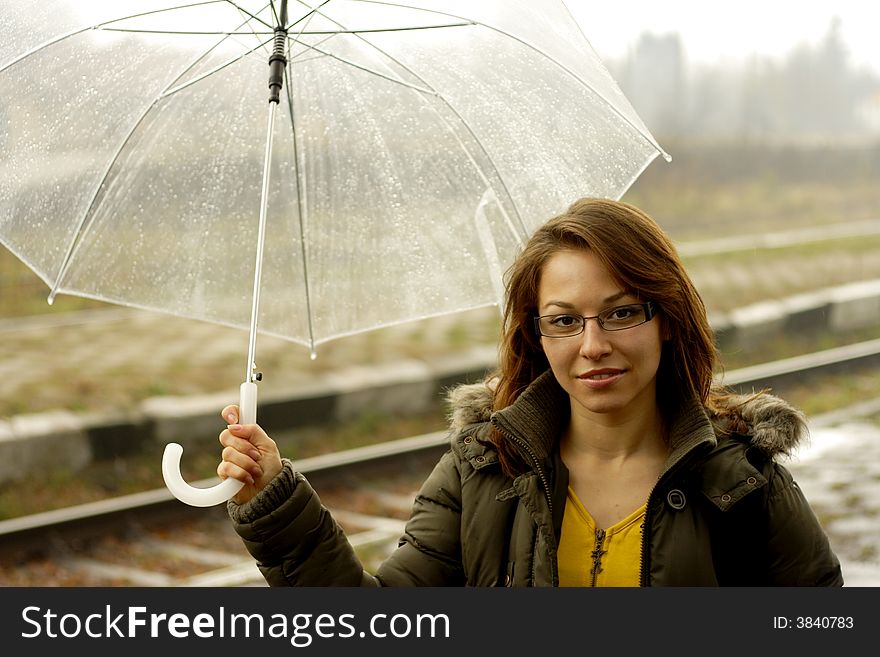 The girl with an umbrella stands under rain