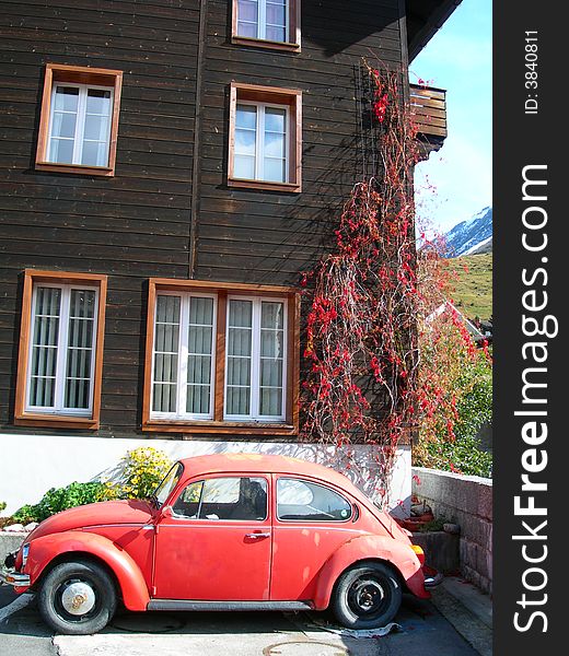 Red old volkswagen car parked next to dark house