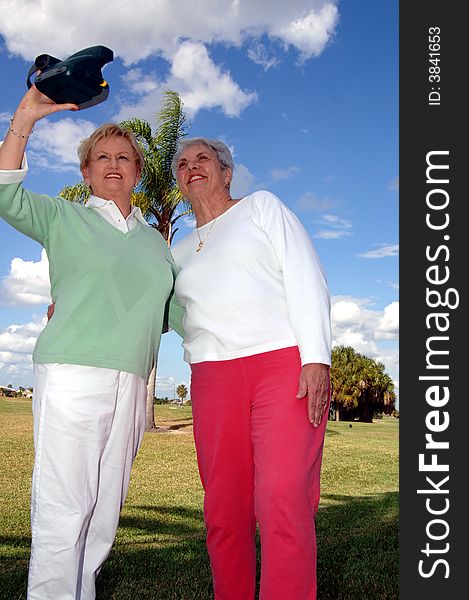 Senior women outdoors taking an instant photo together. Senior women outdoors taking an instant photo together