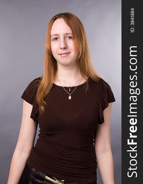 The young girl in brown shirt-blouse on a grey background