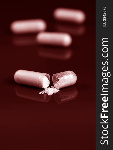 Close up of pill spilling white powder on red background. Close up of pill spilling white powder on red background