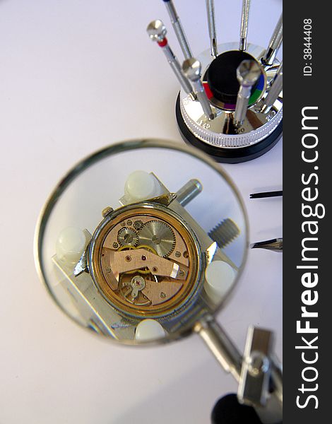 A view with a watch mechanism under a magnifier glass. A view with a watch mechanism under a magnifier glass