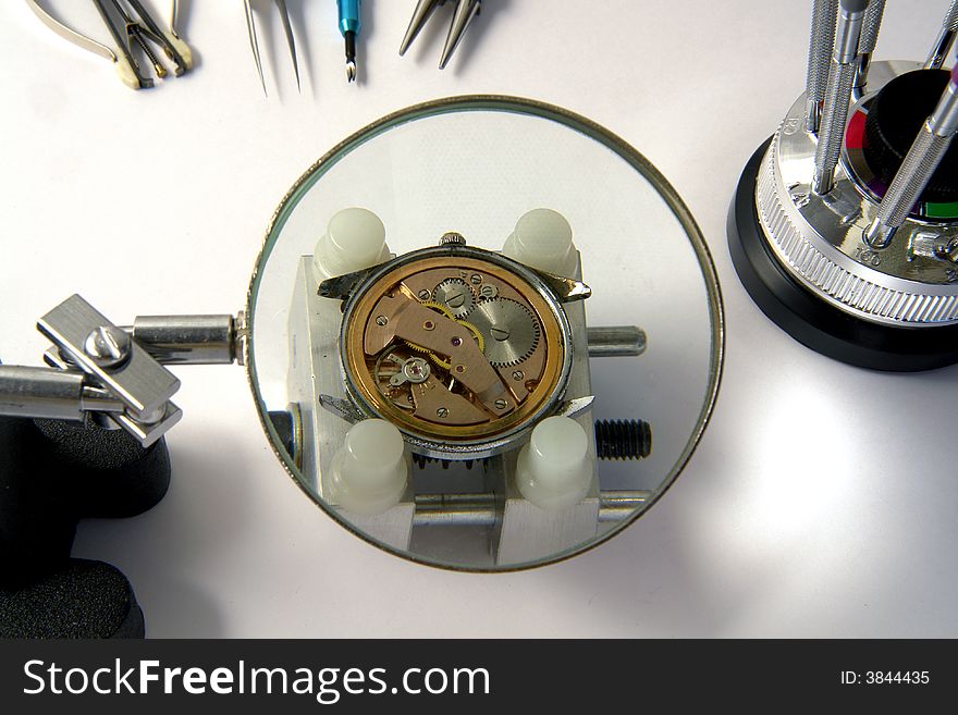 A view with a watch mechanism under a magnifier glass. A view with a watch mechanism under a magnifier glass