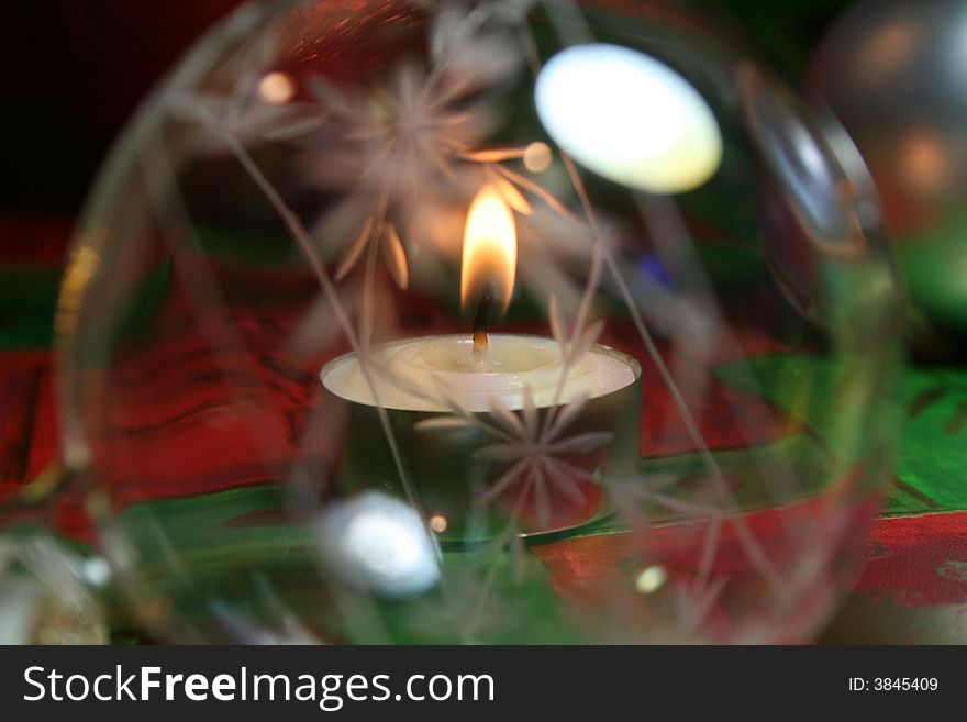 A christmas ornament and candle arranged on festive background holiday paper. A christmas ornament and candle arranged on festive background holiday paper