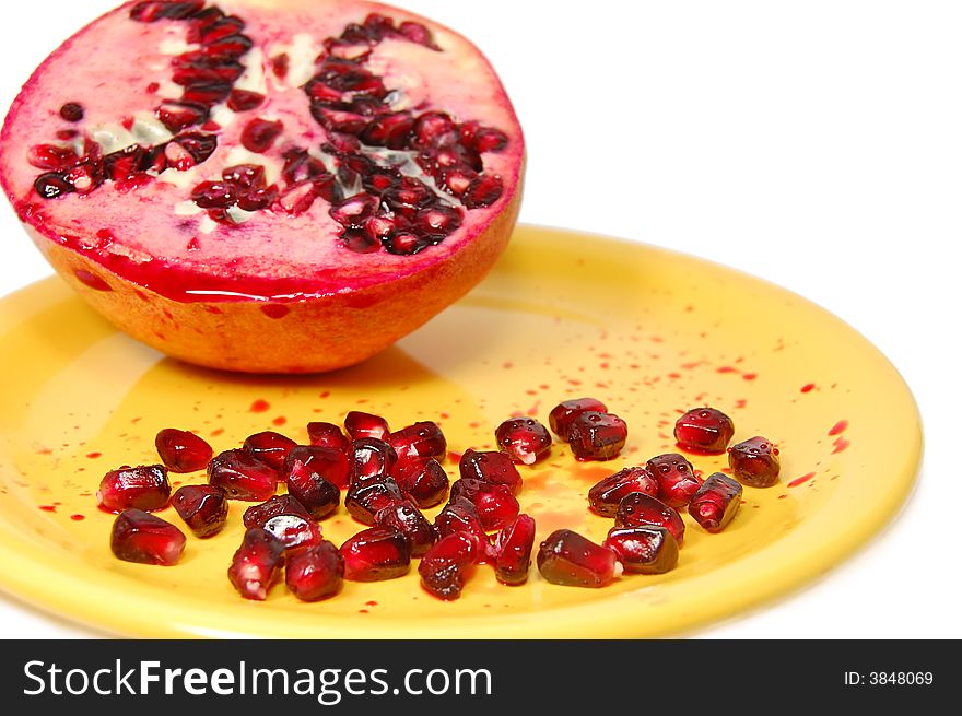 Sliced pomegranate with juice and seeds on yellow plate. Sliced pomegranate with juice and seeds on yellow plate