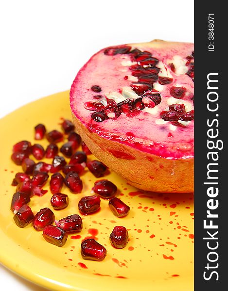 Sliced pomegranate with juice and seeds on yellow plate
