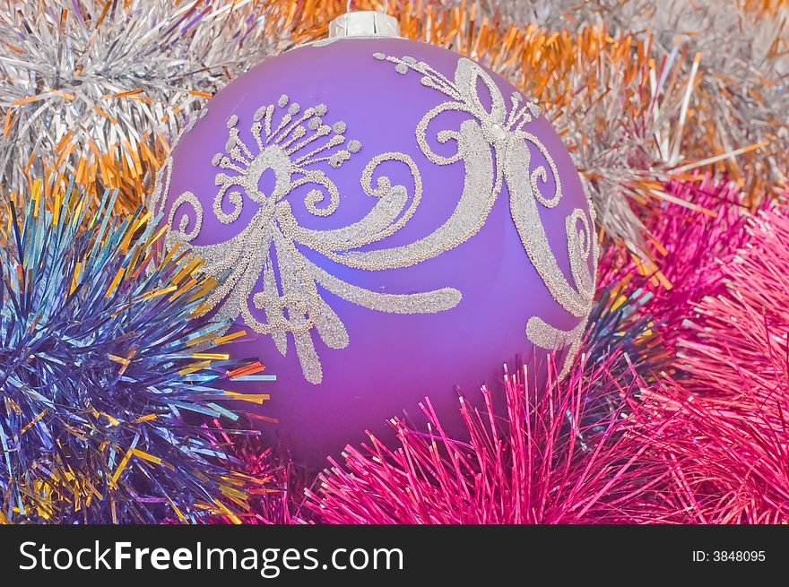 Christmas tree ball in the middle of coloured tinsel. Christmas tree ball in the middle of coloured tinsel