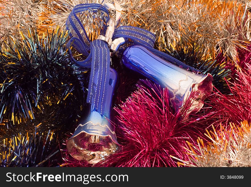 Two Christmas tree bells at the middle of coloured tinsel. Two Christmas tree bells at the middle of coloured tinsel