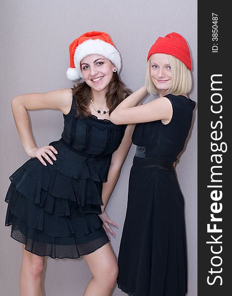 Two beautiful girls in red christmas caps and in black clothes