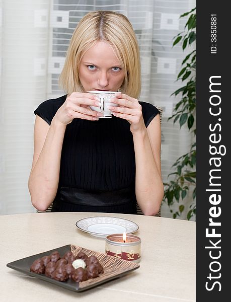 A beautiful woman in black clothes at the table has coffee