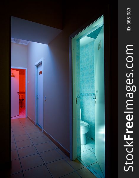 Mysterious corridor with blue light and opened doors to medical cabinet with red light and usual toilet. Mysterious corridor with blue light and opened doors to medical cabinet with red light and usual toilet.
