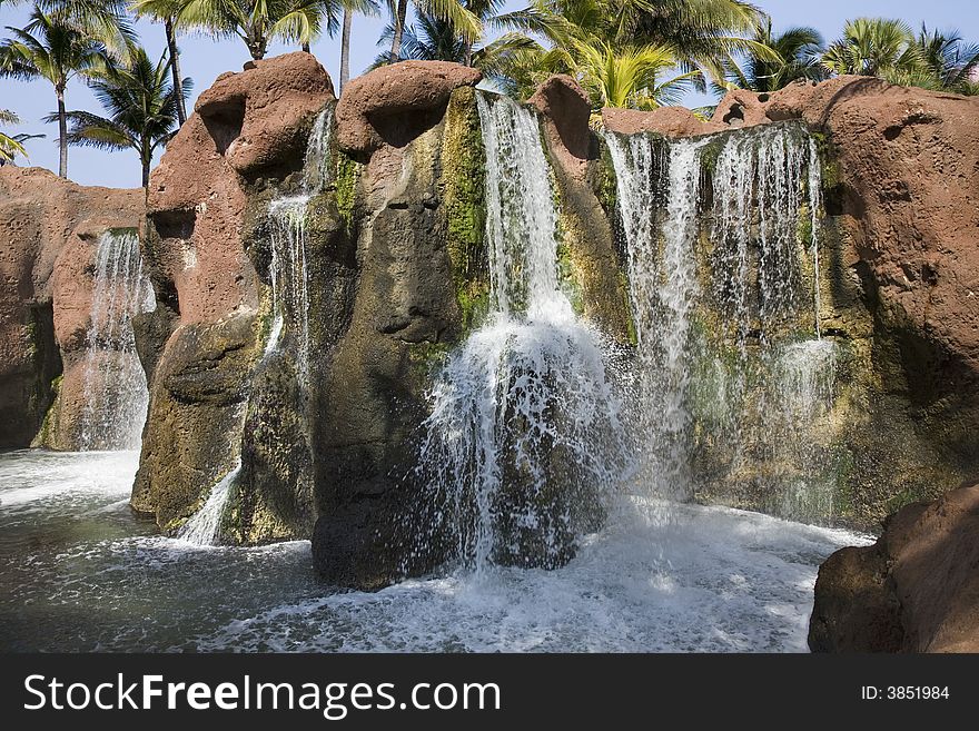 Multiple tropical waterfalls with palm tree background.