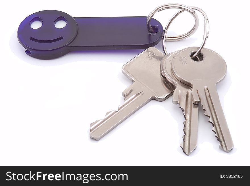 Bunch of keys with dark blue smile trinket isolated on white. Close-up. Bunch of keys with dark blue smile trinket isolated on white. Close-up.