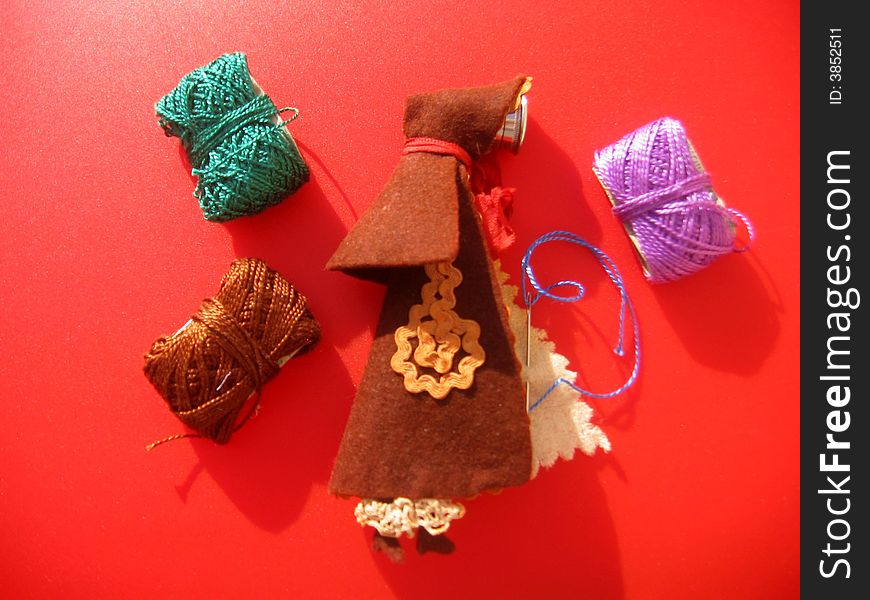 A thinner felt cape with a thimble and needles inside. You also can see three cotton reels. A thinner felt cape with a thimble and needles inside. You also can see three cotton reels.