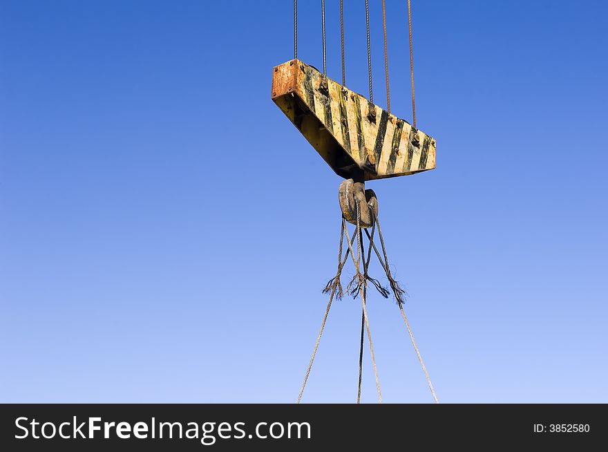 Heavy yellow striped pulley against the blue sky.