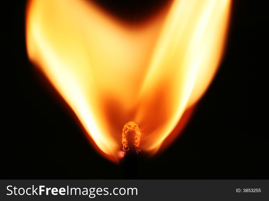 Closeup of burning matchstick on black background