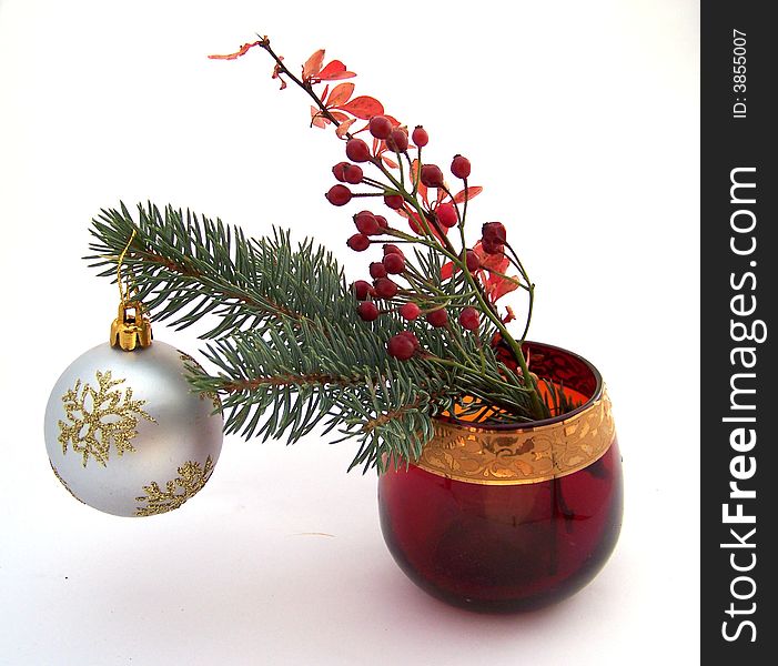 Christmas bouquet of fir-tree brunch with ball and red leaves brunch in red glass vase