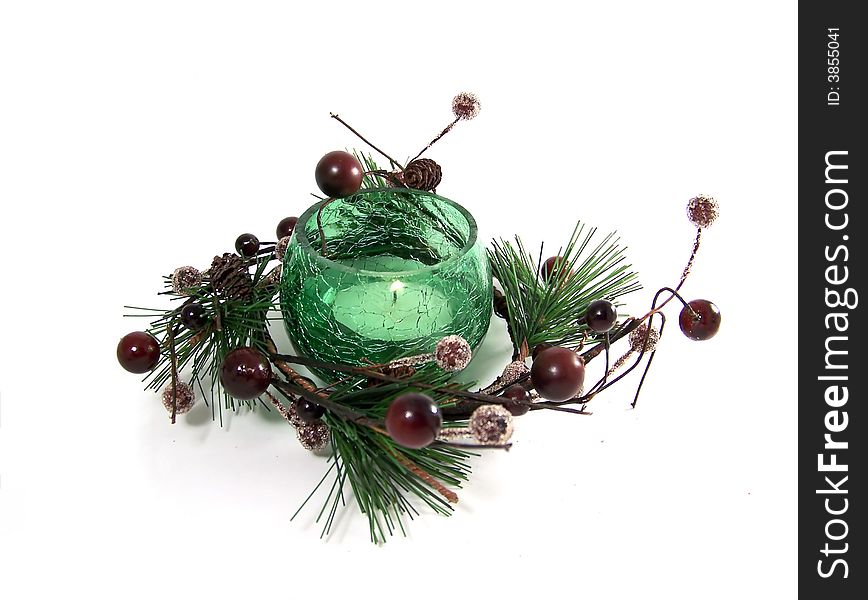 Green glass candle holder with burning candle in small decorative garland. Green glass candle holder with burning candle in small decorative garland