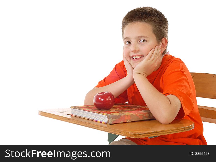 Cute schoolboy ready to learn at his desk; isolated on white