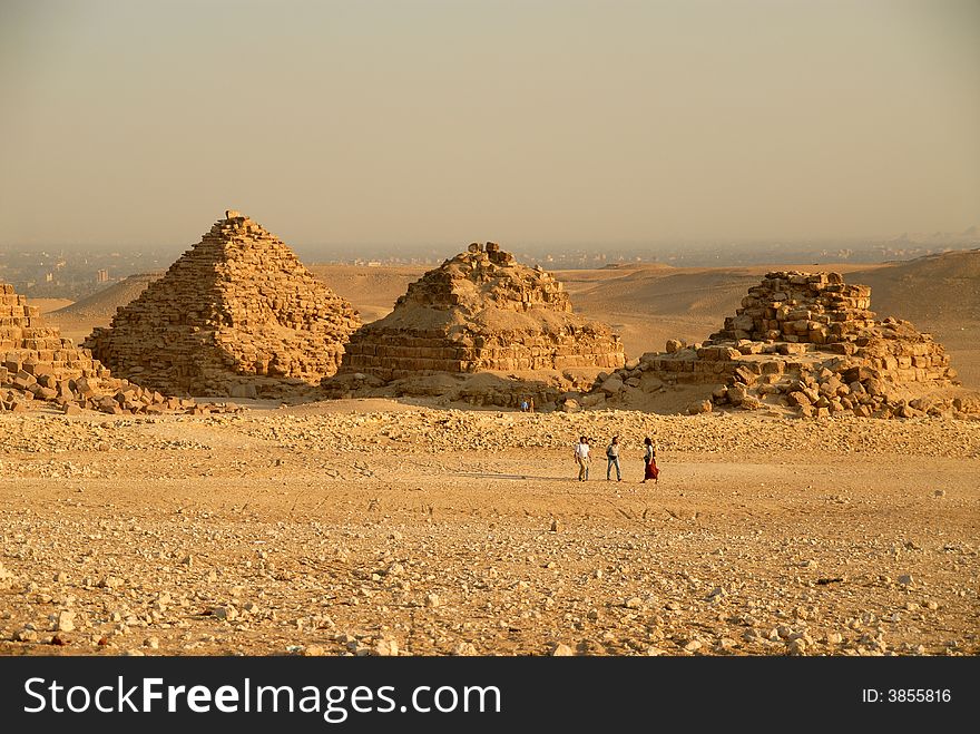 Photo of the three small pyramids at Giza in Cairo with people in the foreground to show perspective.