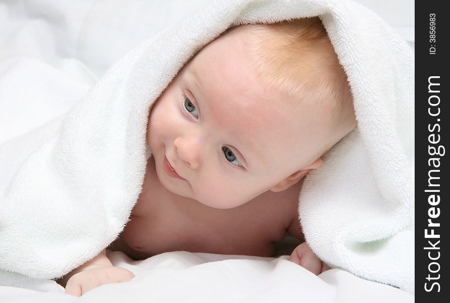 Tot under towel on white background.