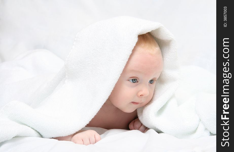 Tot under towel on white background.