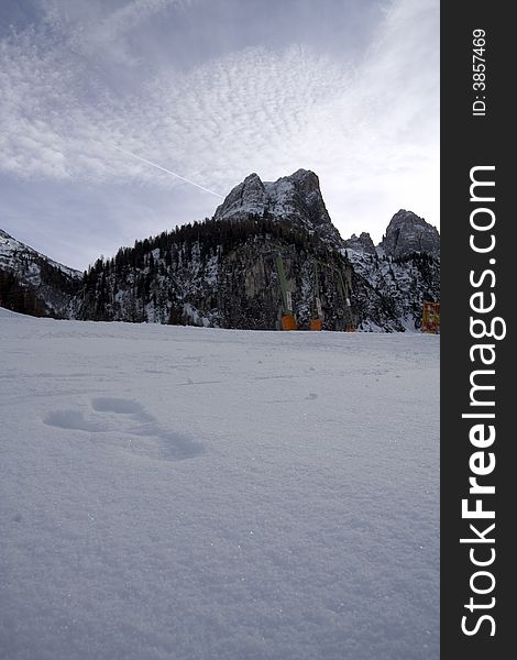 Footprints in the snow at the side of a ski piste and lift