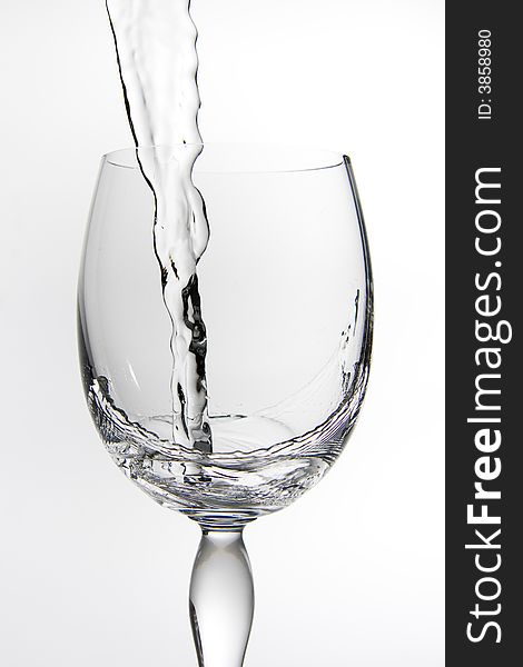 A shot of a wine glass being filled with water, white background. A shot of a wine glass being filled with water, white background