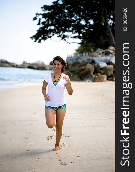 Young smiling woman running on the beach