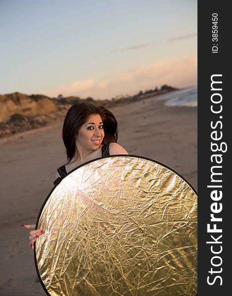 Model holding a Reflector at the Beach at Sunset