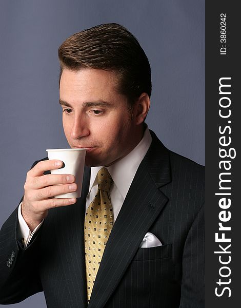 Businessman sips cup of coffee on blue background. Businessman sips cup of coffee on blue background
