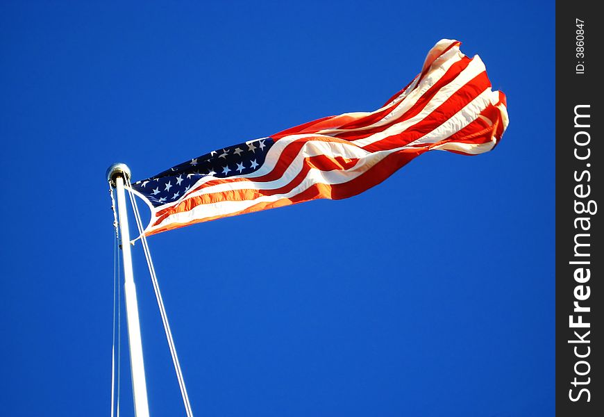 The American Flag waving proudly in the wind tethered to a flag pole. The American Flag waving proudly in the wind tethered to a flag pole.