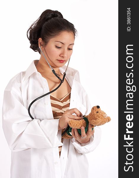 Attractive young female doctor with stethoscope checking a teddy bear