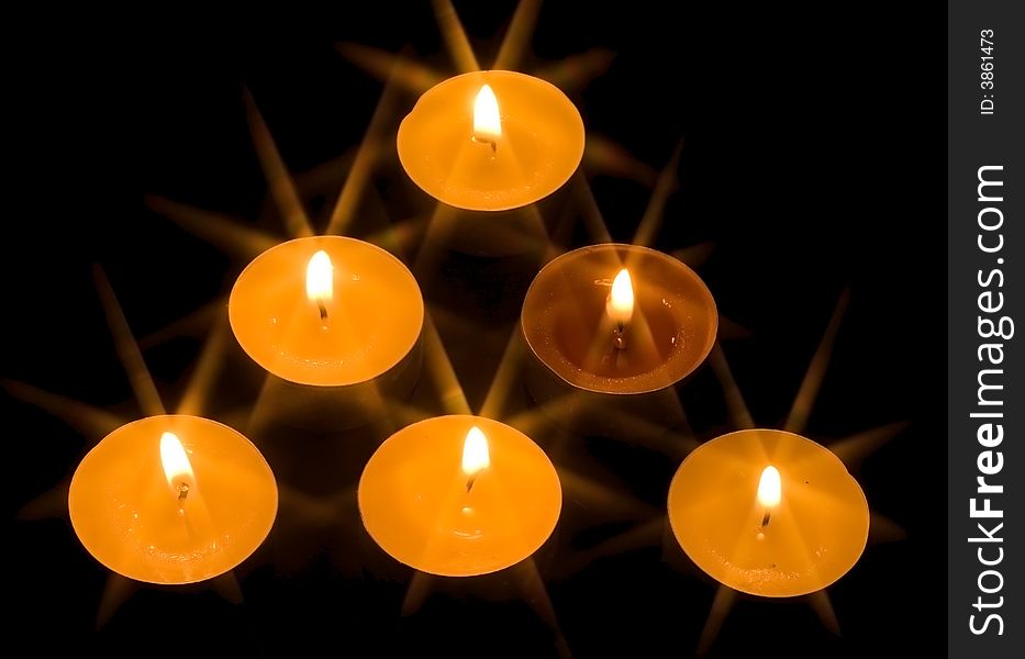 A group of six burning candles on the black background. A group of six burning candles on the black background