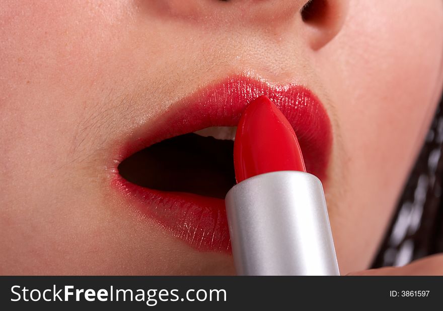 Young beautiful woman applying a red lipstick