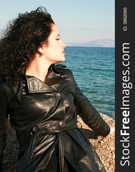 A young woman in leather jacket by the sea
