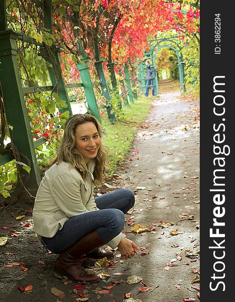 The beautiful blonde in red leaves of grapes