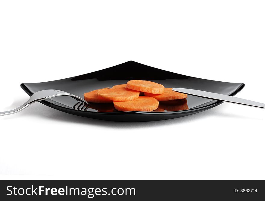 Fork, knife, black plate and carrot. Two. Objects over white.