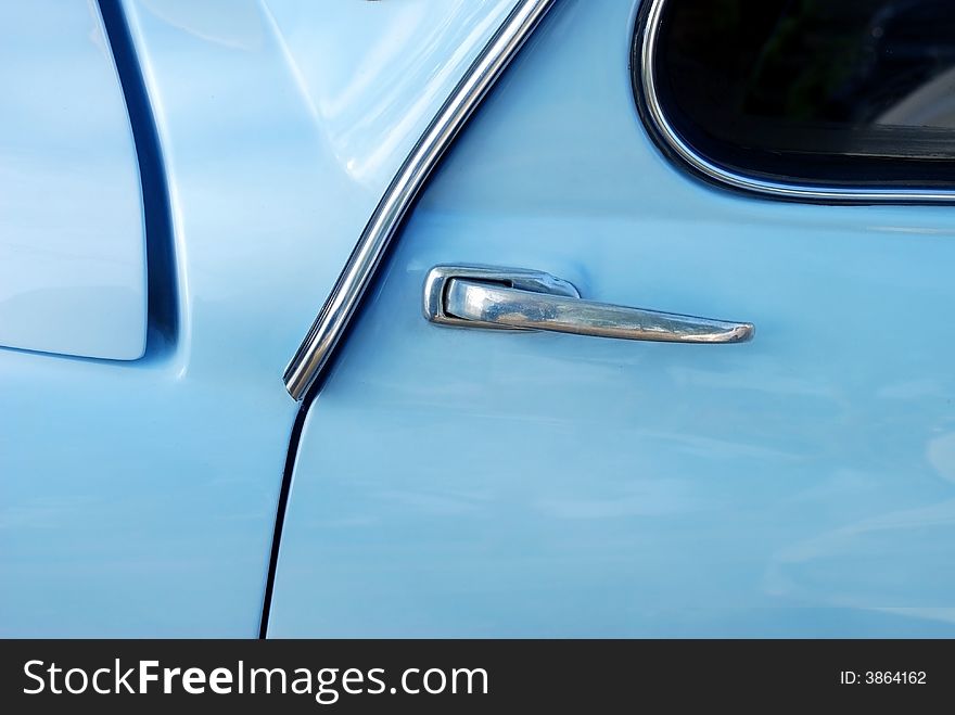 Detail image of the door handle of a light blue Fiat 600. Detail image of the door handle of a light blue Fiat 600