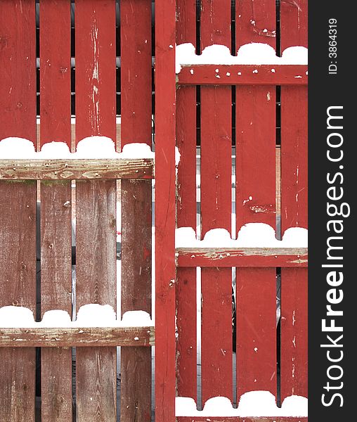 Red fence with snow piles after a snowstorm