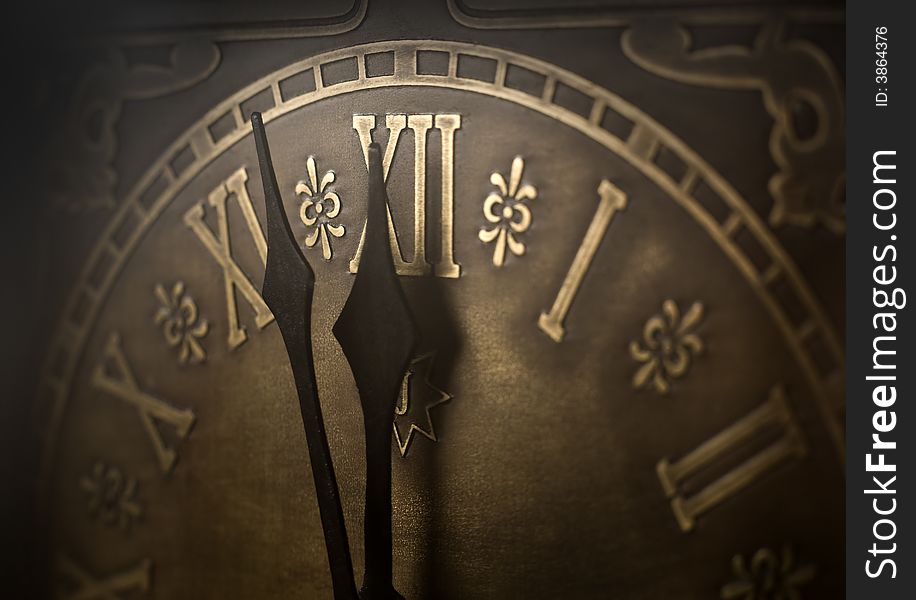 Old clock with roman numerals. Selective focus on number XII and minute hand. Intentional vignetting. Old clock with roman numerals. Selective focus on number XII and minute hand. Intentional vignetting.