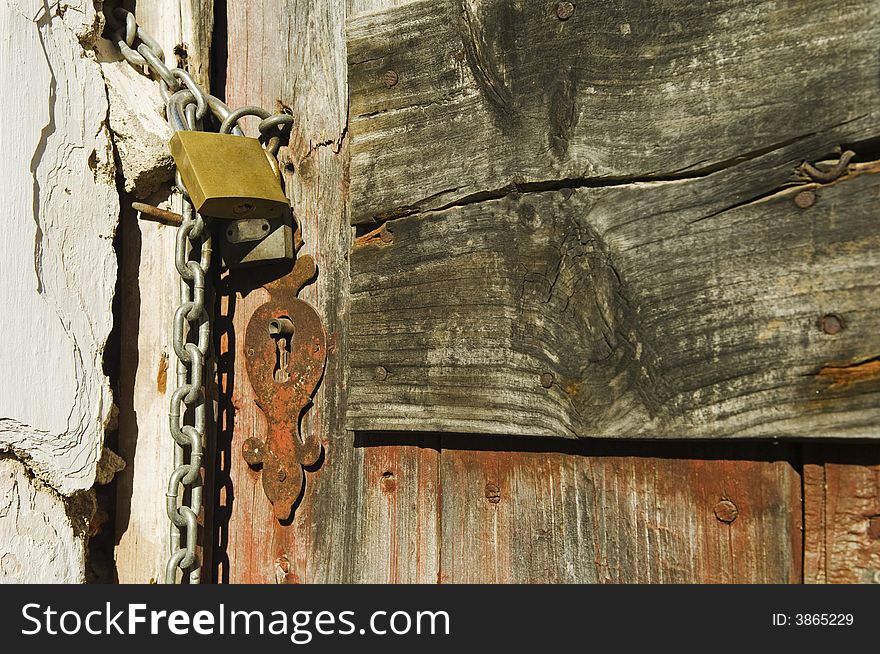 Old drab door secured with a padlock and iron chain. Old drab door secured with a padlock and iron chain.