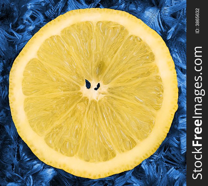 A juicy slice of lemon isolated on a blue background. A juicy slice of lemon isolated on a blue background.