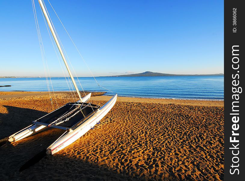 Early morning beach scene with sailboat in foreground