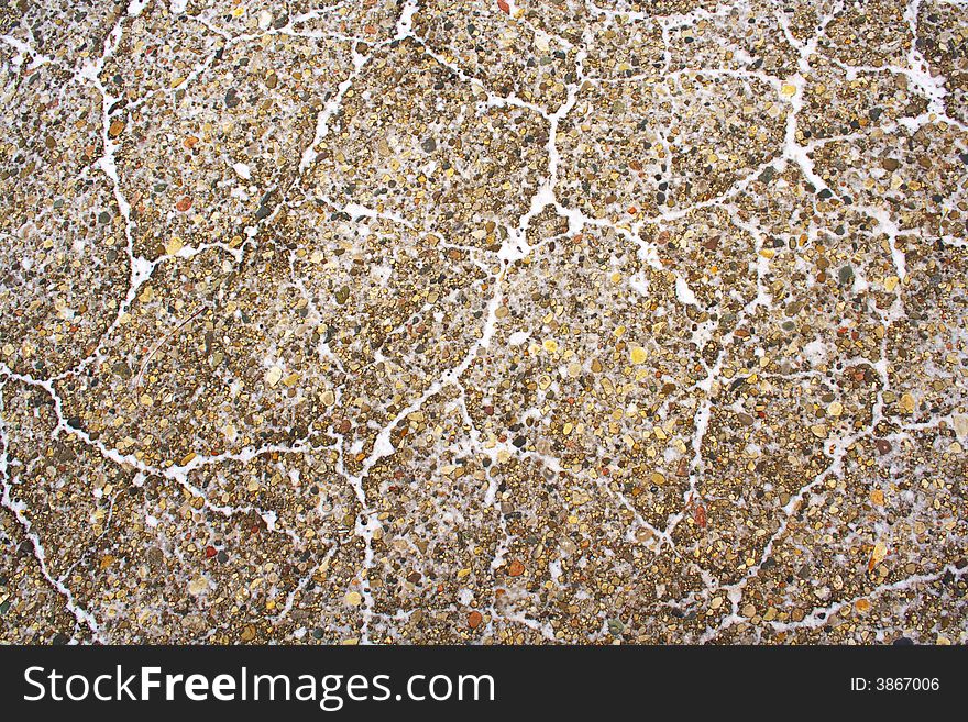 Colorful ground texture with cracks filled with snow.