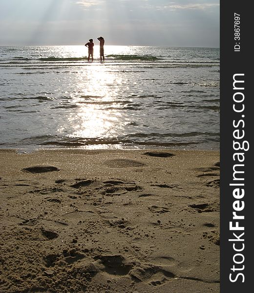 A man and woman standing in shallow water at the beach in the afternoon. A man and woman standing in shallow water at the beach in the afternoon