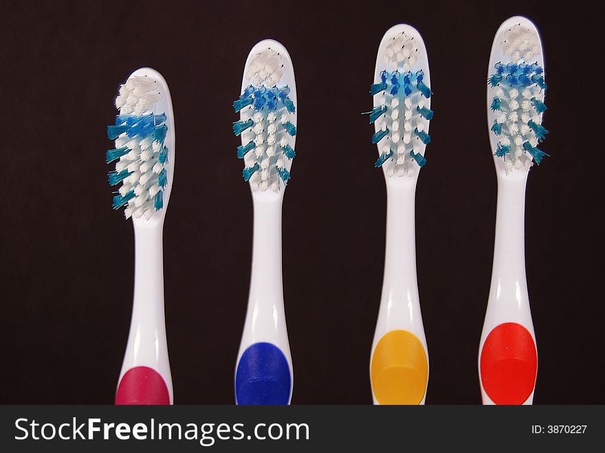 Row of toothbrushes on black.